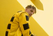 A model in a bold yellow and black leather jacket against a yellow wall, showing what is alt fashion