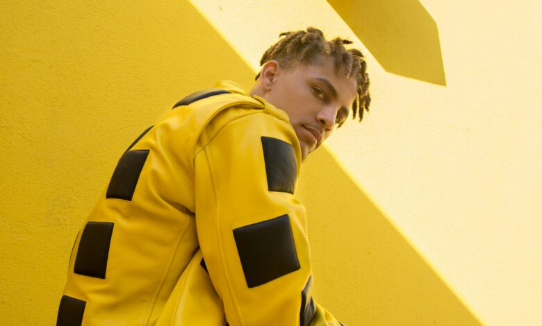 A model in a bold yellow and black leather jacket against a yellow wall, showing what is alt fashion