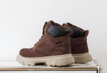 A pair of UGG boots being gently cleaned at home with a suede brush, soft cloth, and mild cleaning solution.