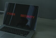 A person using a home computer with a digital security shield, lock icon, and warning symbols representing protection from cyber threats.