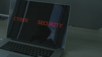 A person using a home computer with a digital security shield, lock icon, and warning symbols representing protection from cyber threats.