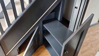Shoe rack for under stairs built as a custom dark cabinet with angled shelves and doors