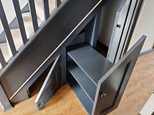 Shoe rack for under stairs built as a custom dark cabinet with angled shelves and doors
