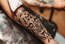 A person examining an unwanted tattoo while researching safe tattoo-removal options and the risks of DIY methods.