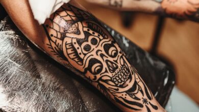 A person examining an unwanted tattoo while researching safe tattoo-removal options and the risks of DIY methods.