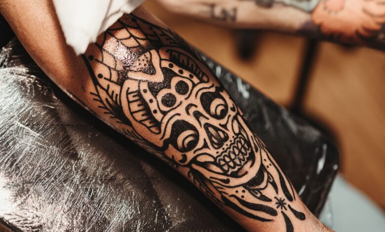 A person examining an unwanted tattoo while researching safe tattoo-removal options and the risks of DIY methods.