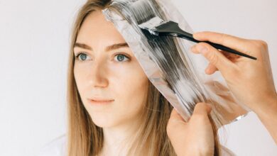A person applying hand-painted highlights to sections of hair at home to create a soft balayage effect.