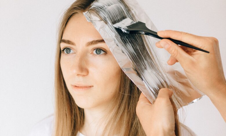 A person applying hand-painted highlights to sections of hair at home to create a soft balayage effect.