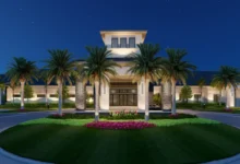 GL Homes clubhouse entrance lit up at night with palm trees and landscaped grounds
